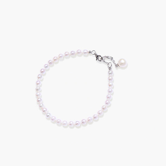 Delicate bracelet featuring lustrous freshwater pearls and a singular drop pearl on an adjustable chain.