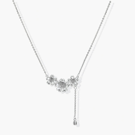 Delicate silver-toned lariat necklace featuring three flower charms and a charming bud pendant for versatile elegance.