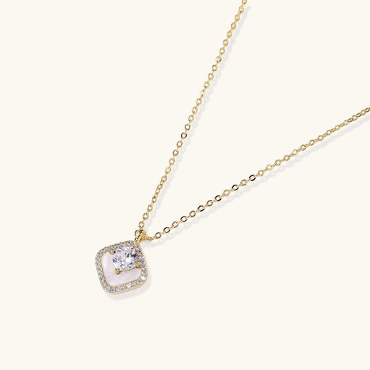 Cushion-shaped pendant featuring a clear faceted stone above a cream inlay, elegantly framed by a pavé halo.