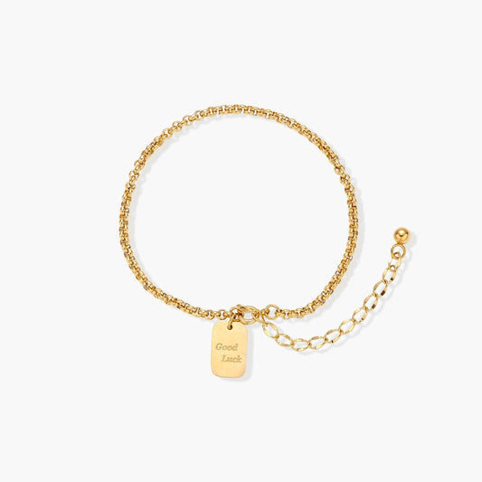 Delicate rolo-chain bracelet featuring a 'Good Luck' engraved tag and an adjustable bead-tipped extender.