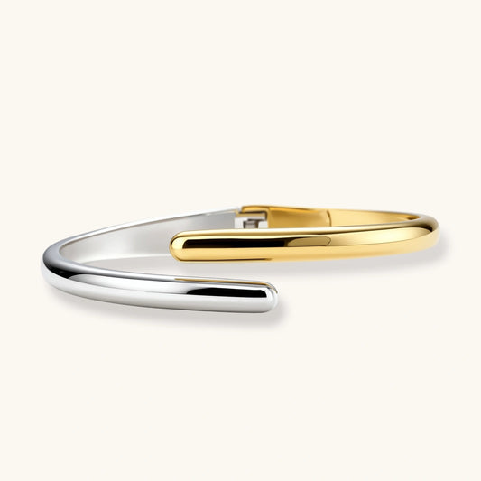 Polished dual-tone cuff bracelet featuring overlapping silver and gold bands with rounded tapered ends.