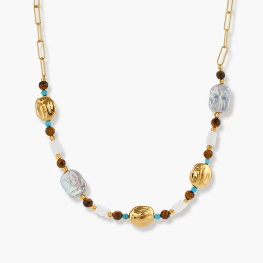 Gold-plated beaded necklace with iridescent baroque pearls, turquoise stones, and brown natural beads on neutral background.