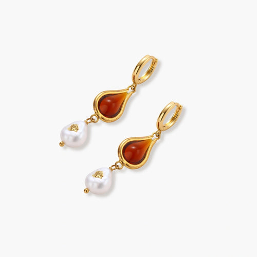 Gold-plated drop earrings featuring amber teardrops and white baroque pearls on light background.