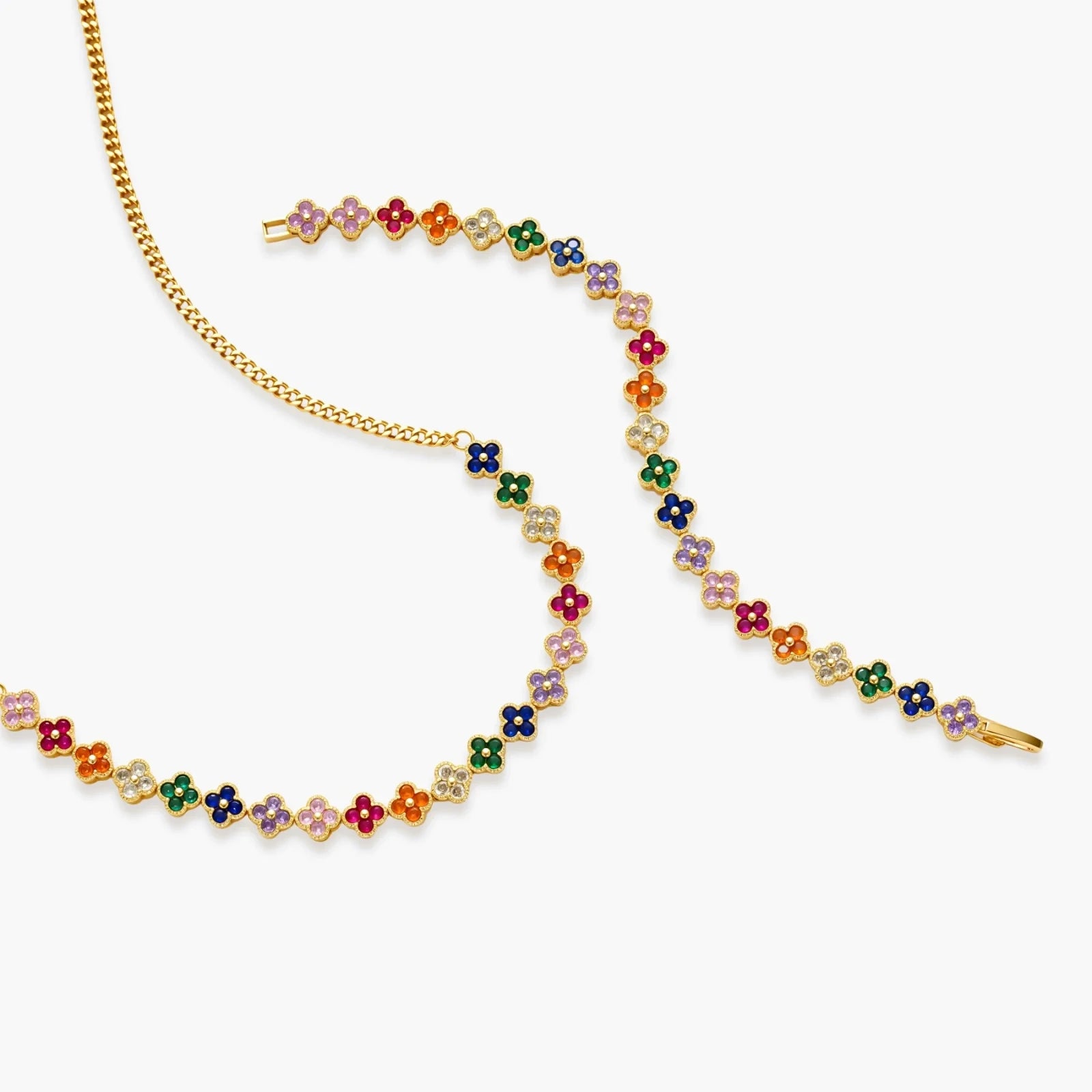 Colorful four-leaf clover jewelry set with rainbow cubic zirconia stones in gold-plated setting on white background