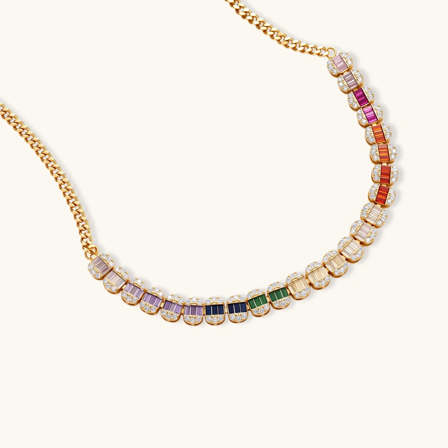 Gold-plated jewelry set featuring rainbow baguette-cut cubic zirconia stones in geometric design on cream background