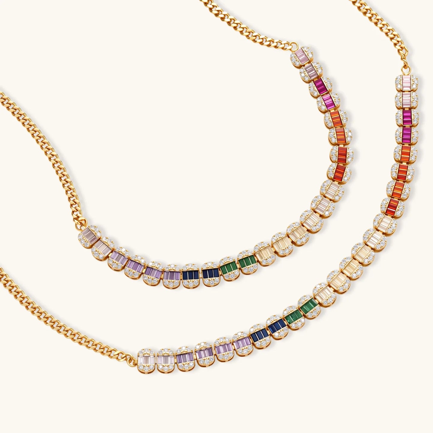 Gold-plated jewelry set featuring rainbow baguette-cut cubic zirconia stones in geometric design on cream background