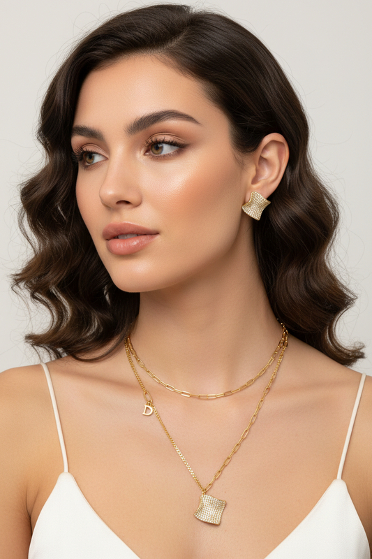 Gold-plated wavy jewelry set with crystal detailing featuring necklace with dual chains and matching textured earrings