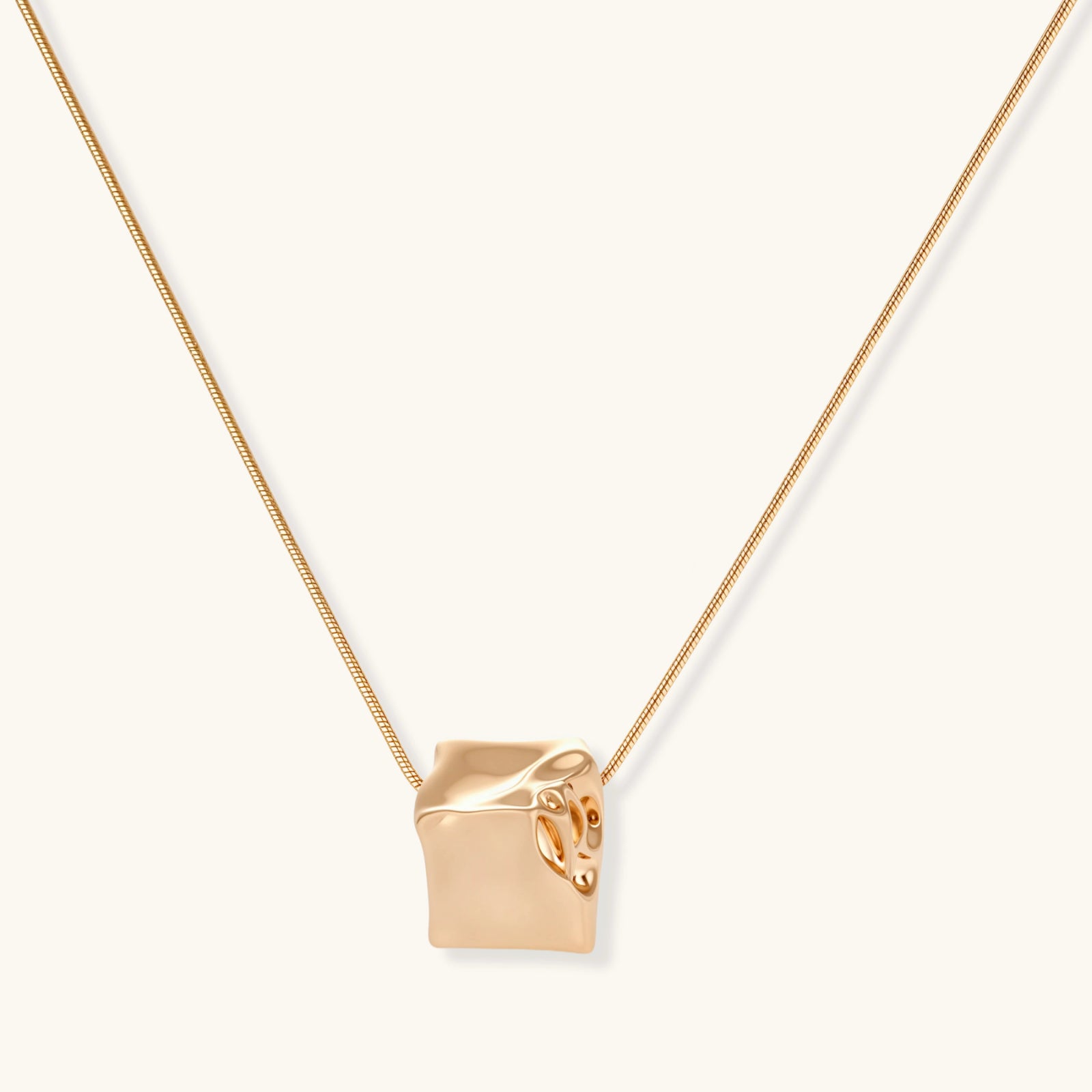 Modern cube pendant with liquid metal draping detail on adjustable chain, available in gold and silver finishes