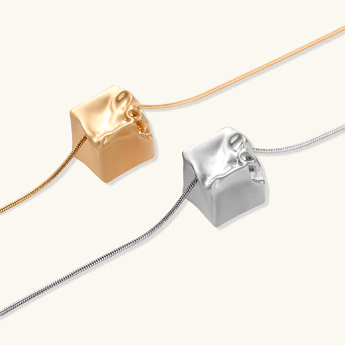 Modern cube pendant with liquid metal draping detail on adjustable chain, available in gold and silver finishes