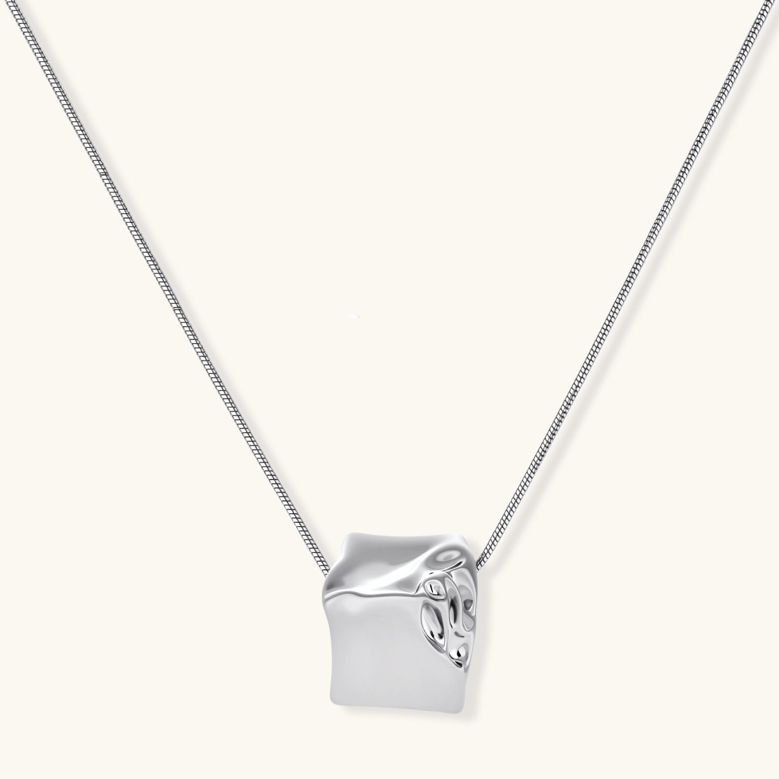Modern cube pendant with liquid metal draping detail on adjustable chain, available in gold and silver finishes