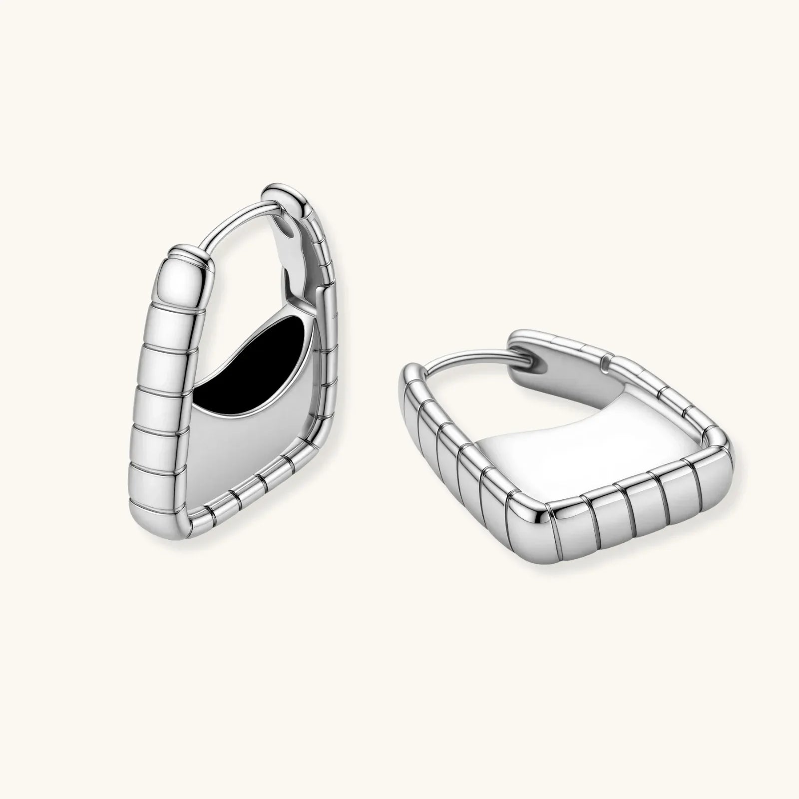 Close-up of platinum-plated sterling silver hoop earrings with horizontal textured grooves on white background.