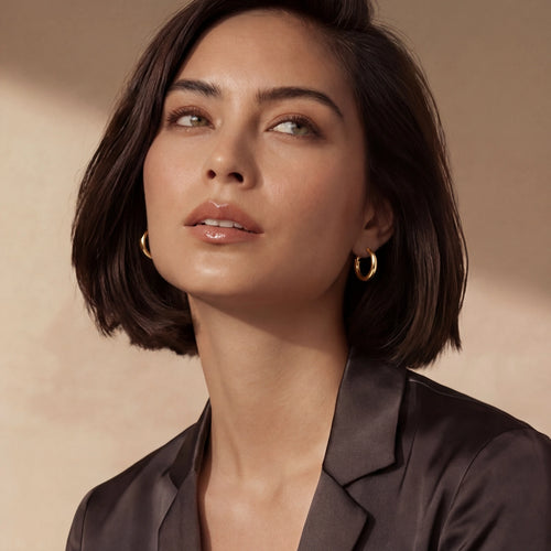 Medium-sized polished gold hoops elegantly worn close to the lobe, showcasing timeless sophistication.