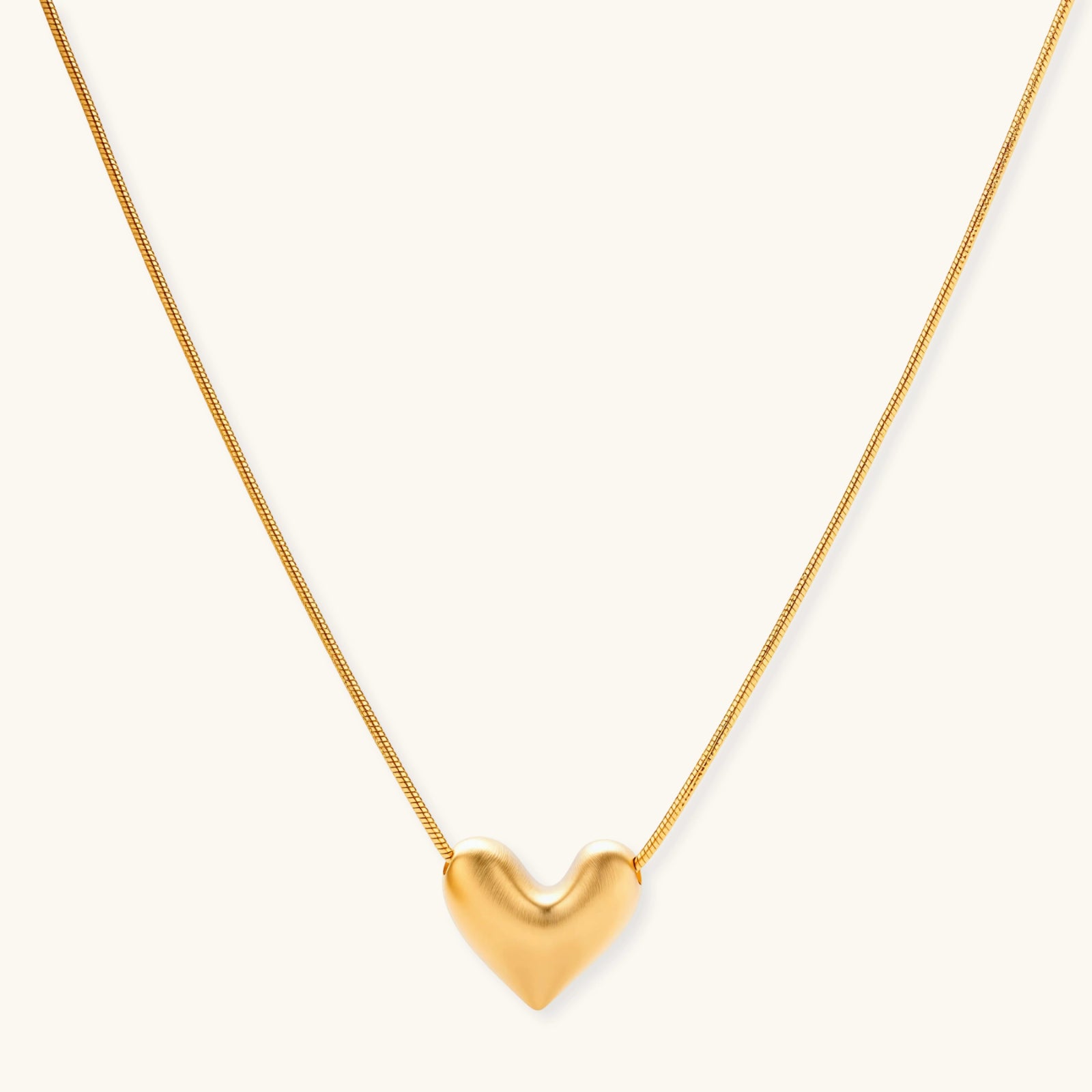 Dainty 18K gold-plated sterling silver necklace with small heart pendant on delicate chain against cream background.