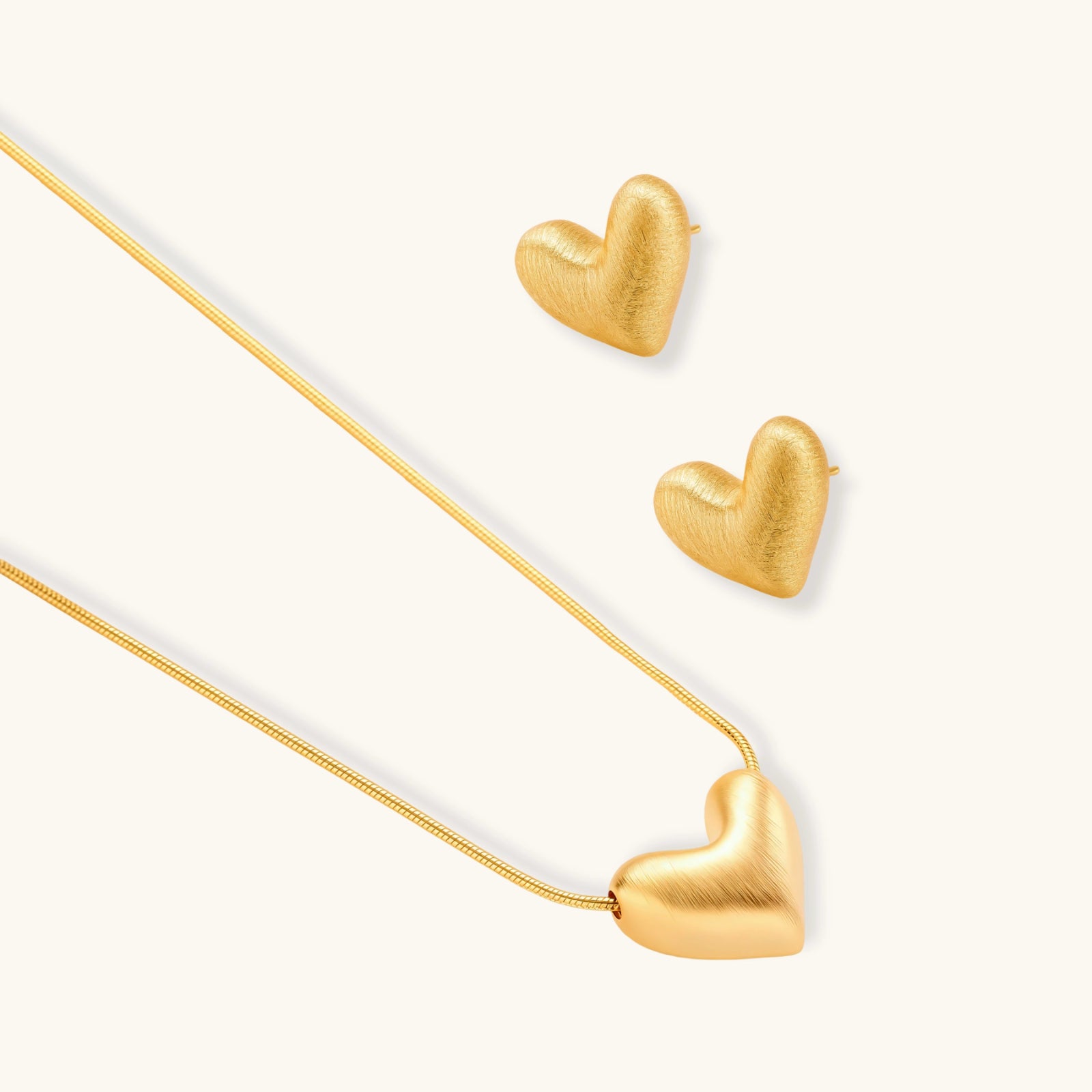 Dainty 18K gold-plated sterling silver necklace with small heart pendant on delicate chain against cream background.