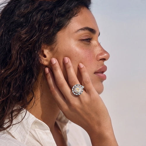 A hand adorned with the Cosmic Spinner Ring, showcasing a honey-gold cabochon and intricate celestial designs.
