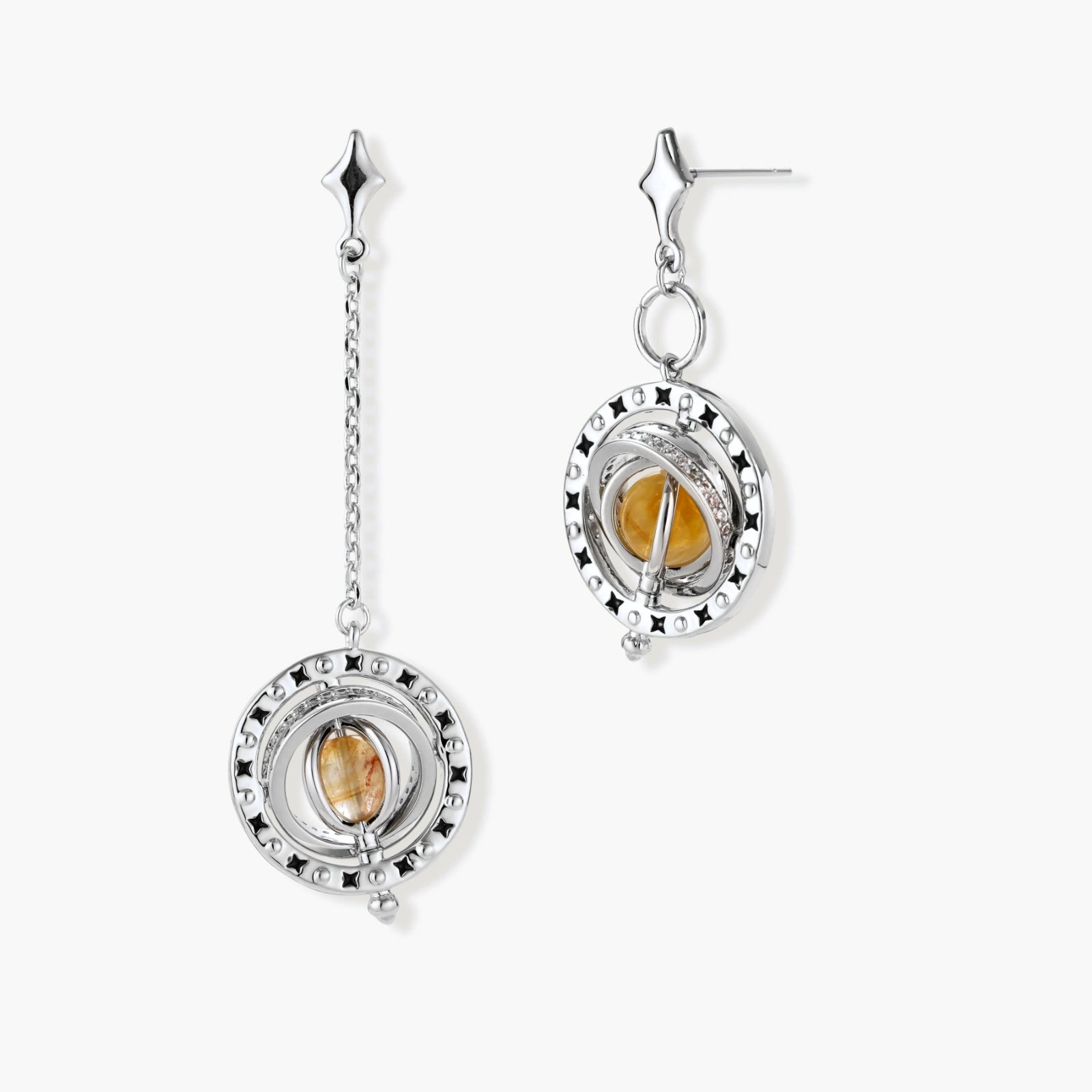 Asymmetrical earrings featuring a star-shaped post, silver-toned ring with black enamel stars, and a honey-gold cabochon.
