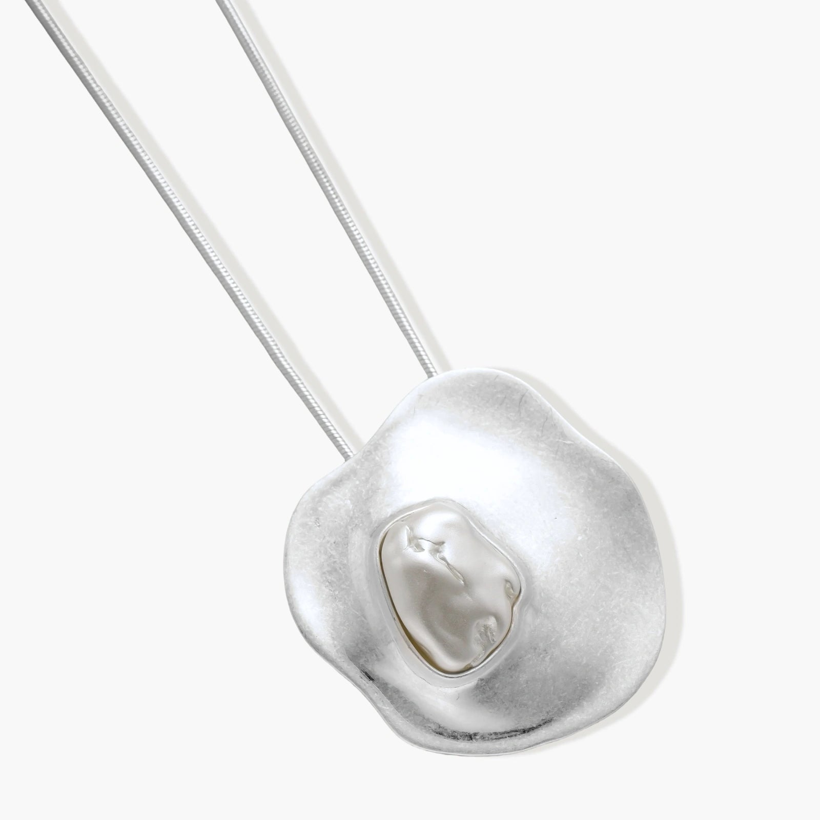 Organic curved earrings and necklace featuring baroque pearls in eco-zinc alloy settings on neutral background