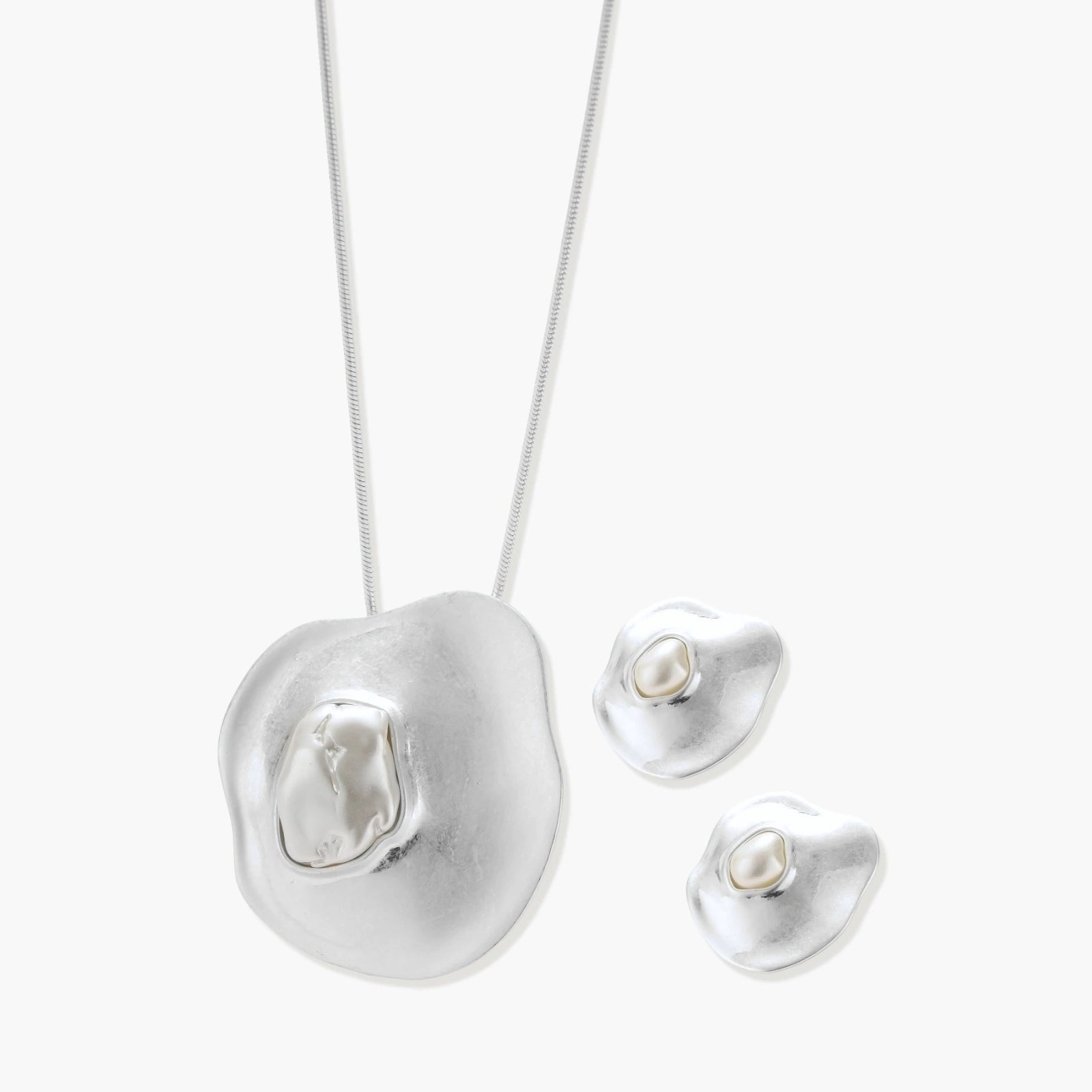 Organic curved earrings and necklace featuring baroque pearls in eco-zinc alloy settings on neutral background