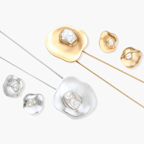 Organic curved earrings and necklace featuring baroque pearls in eco-zinc alloy settings on neutral background