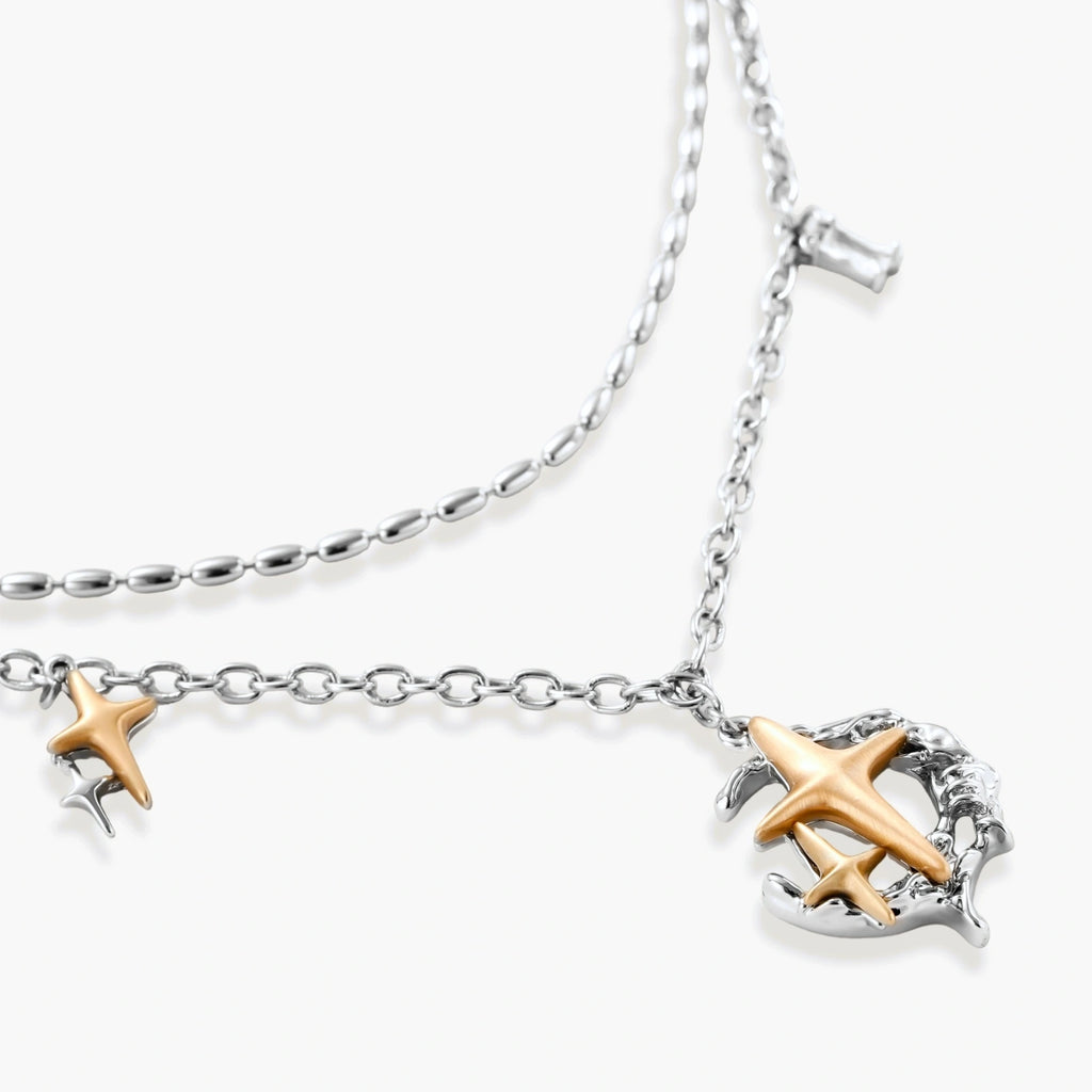 Delicate eco-brass jewelry set featuring gold star and silver moon crescents with clear zirconia crystal drops on cream background