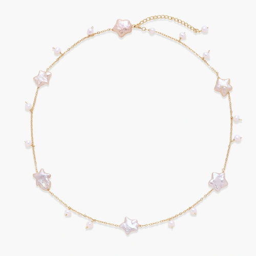 Gold vermeil chain with iridescent star-shaped baroque pearls and small round freshwater pearl drops on cream background.