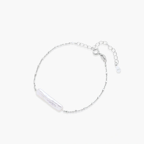 Minimalist bracelet featuring a long, rippled baroque pearl on a delicate chain with an adjustable extender.