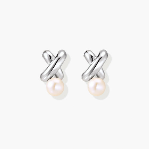 Rhodium-plated silver earrings with twisted X design and freshwater pearl drops on beige background