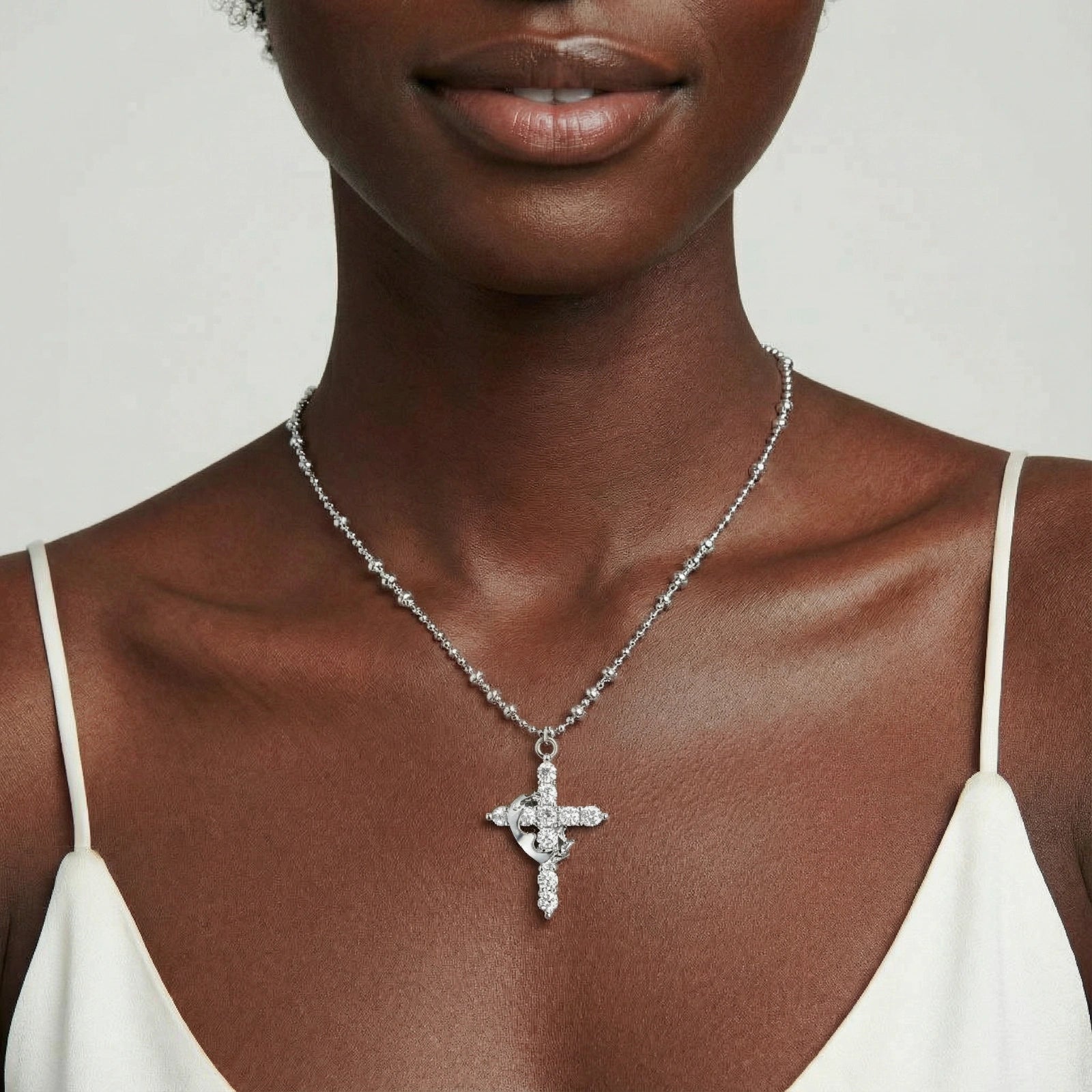 Delicate cross pendant gracefully suspended on a faceted bead chain, embodying elegance and sophistication.