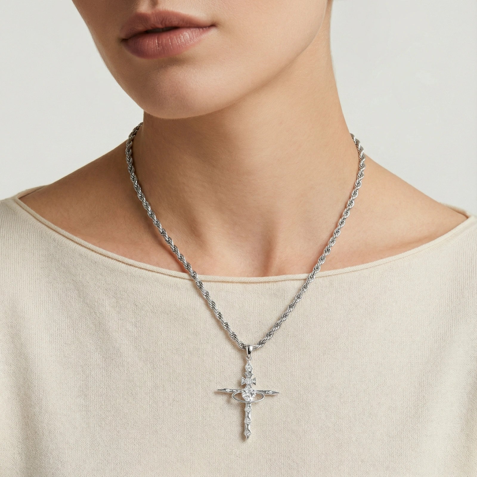 Silver-toned cross pendant elegantly suspended on a twisted rope chain, showcasing timeless sophistication.