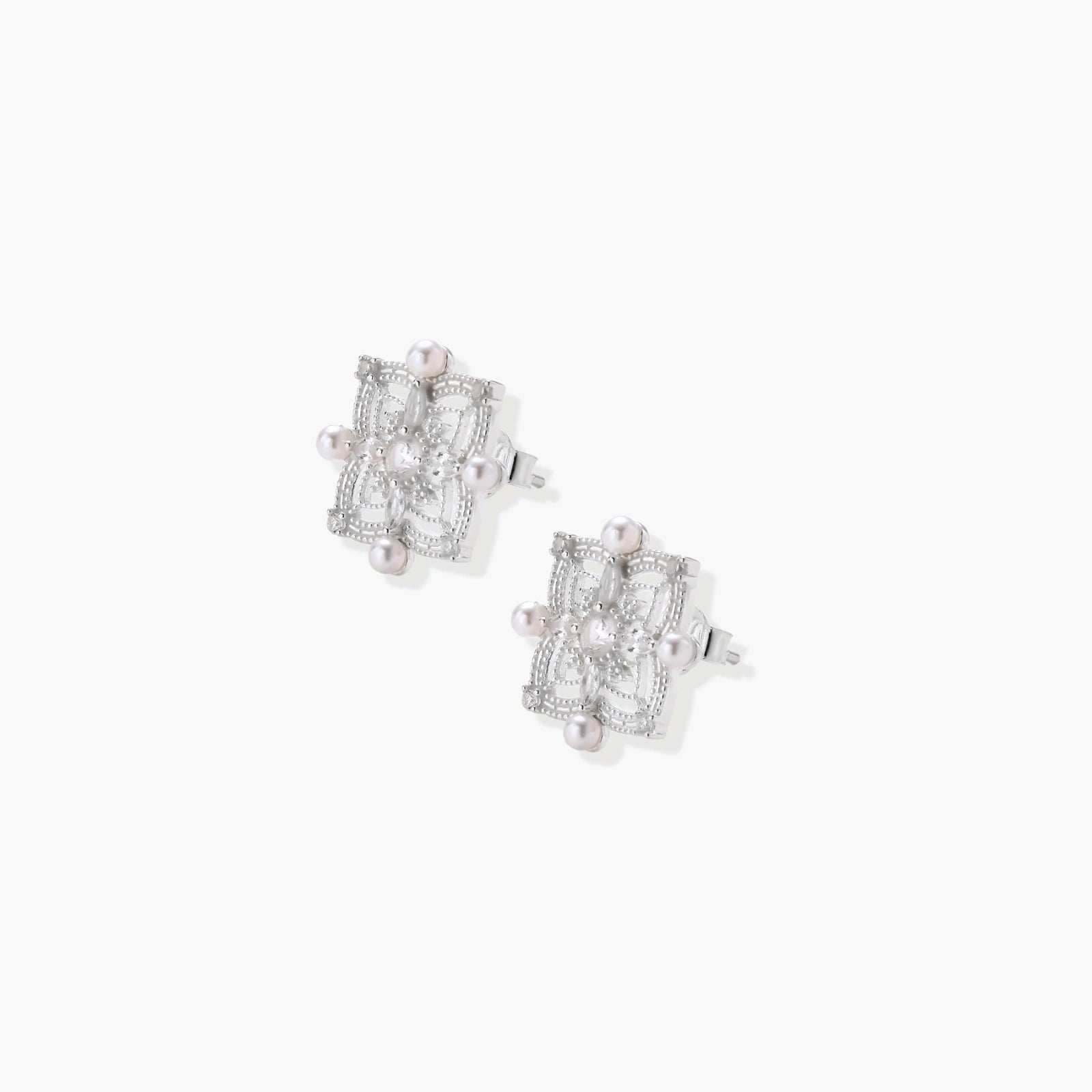 Ornate sterling silver stud earrings with mandala-inspired filigree pattern and four freshwater pearls on beige background