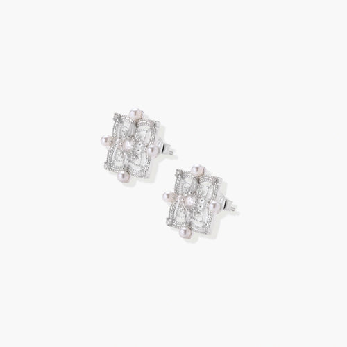 Ornate sterling silver stud earrings with mandala-inspired filigree pattern and four freshwater pearls on beige background