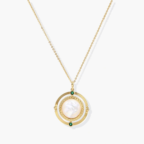 Gold pendant necklace featuring a circular design with a central mother-of-pearl disc and green zirconia accents.