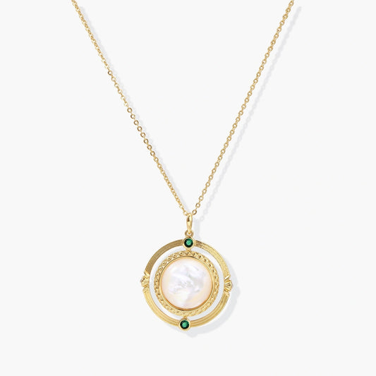 Gold pendant necklace featuring a circular design with a central mother-of-pearl disc and green zirconia accents.