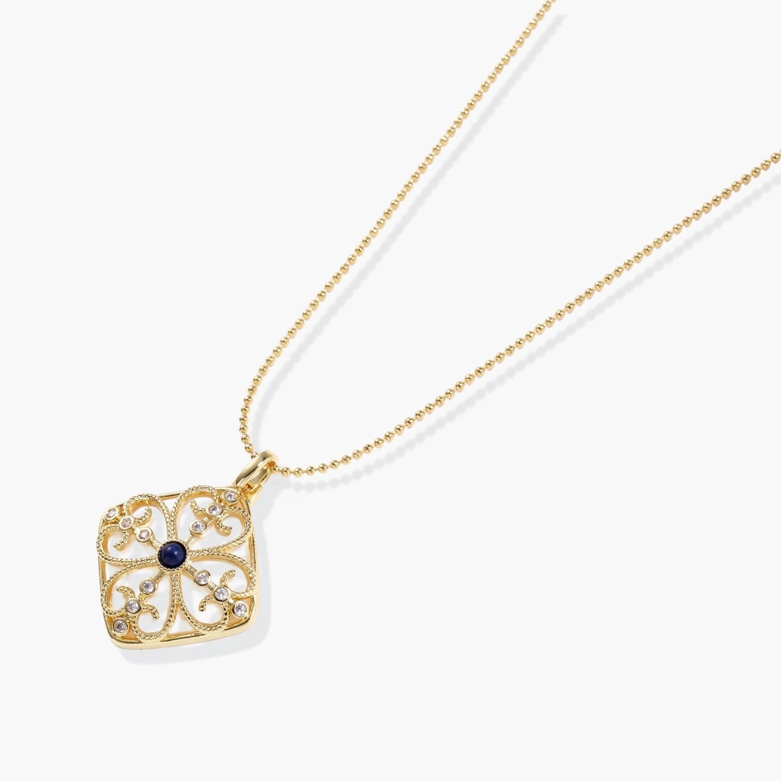 Gold filigree pendant with quatrefoil design, deep blue lapis lazuli center, clear crystal accents on ball chain