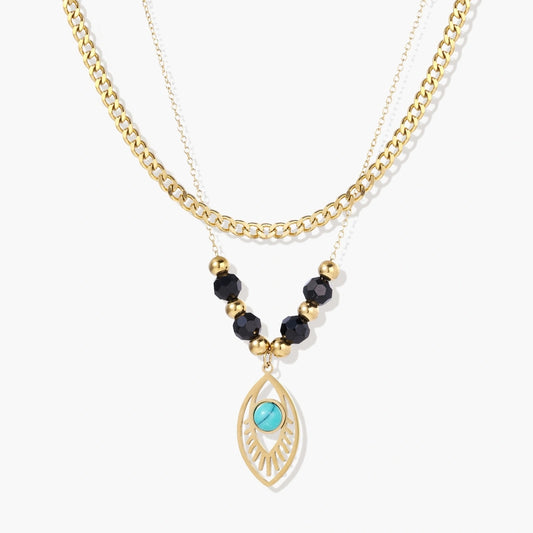 Layered gold necklace featuring a bold curb chain, delicate strand with black quartz beads, and a turquoise eye pendant.