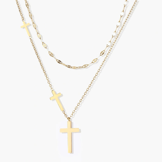 Layered gold necklace set featuring a shorter mirror-link chain and a longer chain with three polished cross pendants.