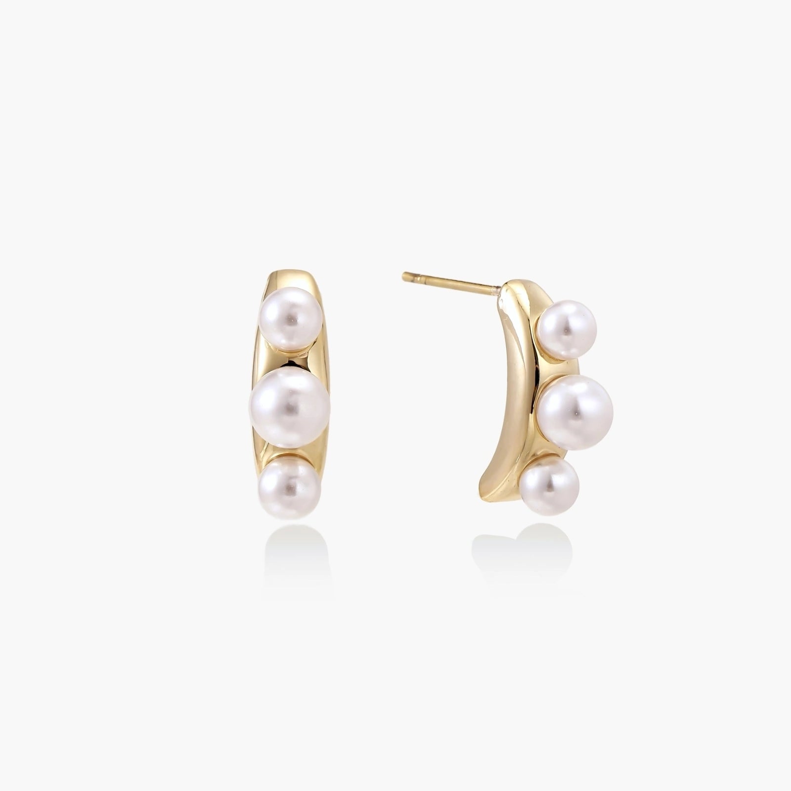 Elegant earrings featuring three freshwater pearls artfully arranged on a polished curved gold bar.