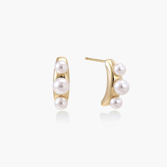 Elegant earrings featuring three freshwater pearls artfully arranged on a polished curved gold bar.