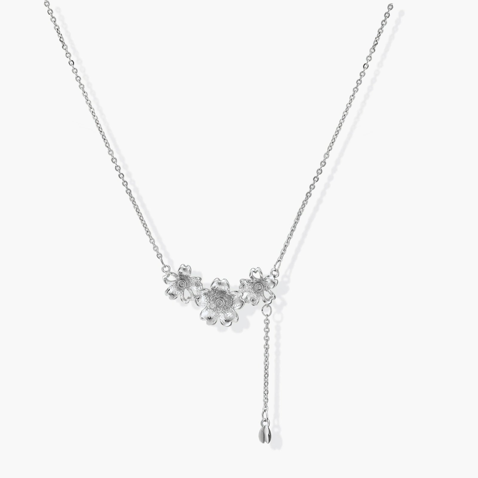 Delicate silver-toned lariat necklace featuring three flower charms and a charming bud pendant for versatile elegance.