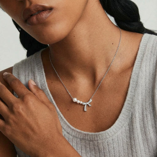Delicate silver-tone necklace featuring three graduated freshwater pearls and a charming pavé bow design.