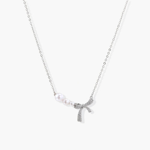 Delicate silver-tone necklace featuring a central pavé bow and three graduated freshwater pearls.