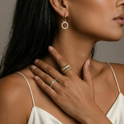Dainty gold huggie earrings featuring a circular charm, elegantly hugging the earlobe for a sophisticated touch.
