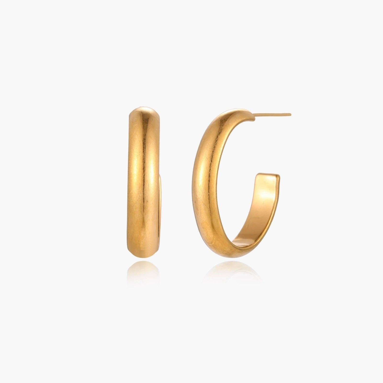 Chunky tubular hoop earrings in warm 14K gold-plated finish with smooth polished surface on cream background.
