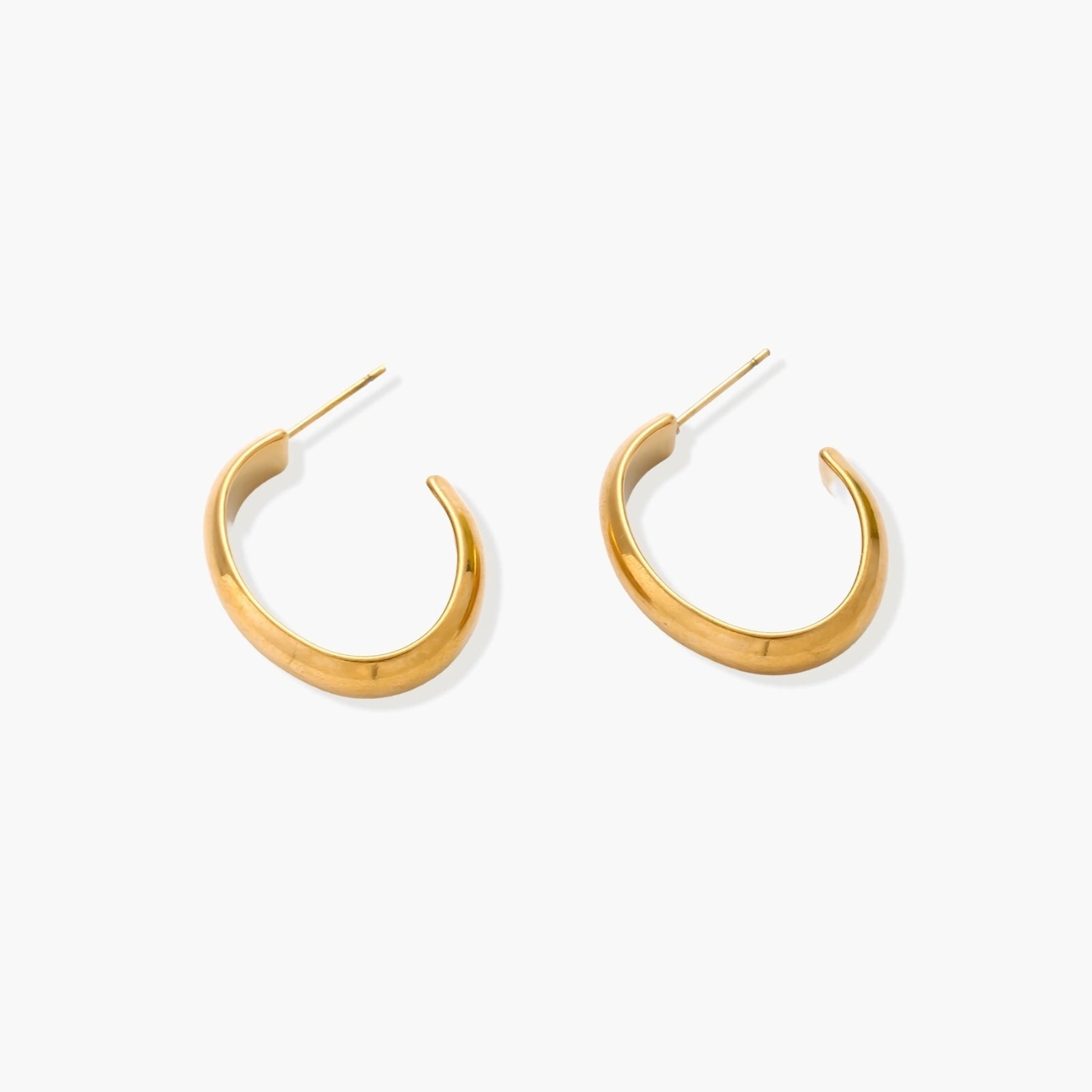Chunky tubular hoop earrings in warm 14K gold-plated finish with smooth polished surface on cream background.