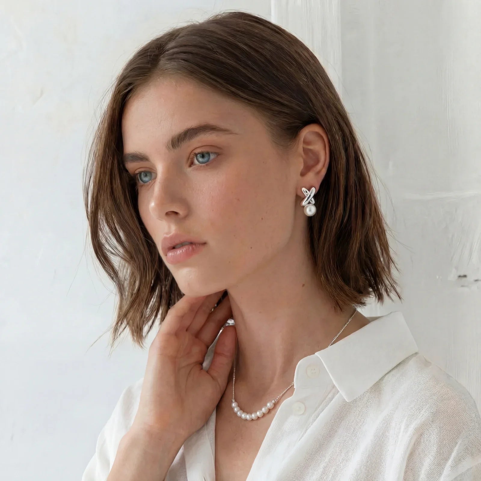 Delicate sterling silver chain necklace with small freshwater pearls arranged in a curved smile arc on cream background.
