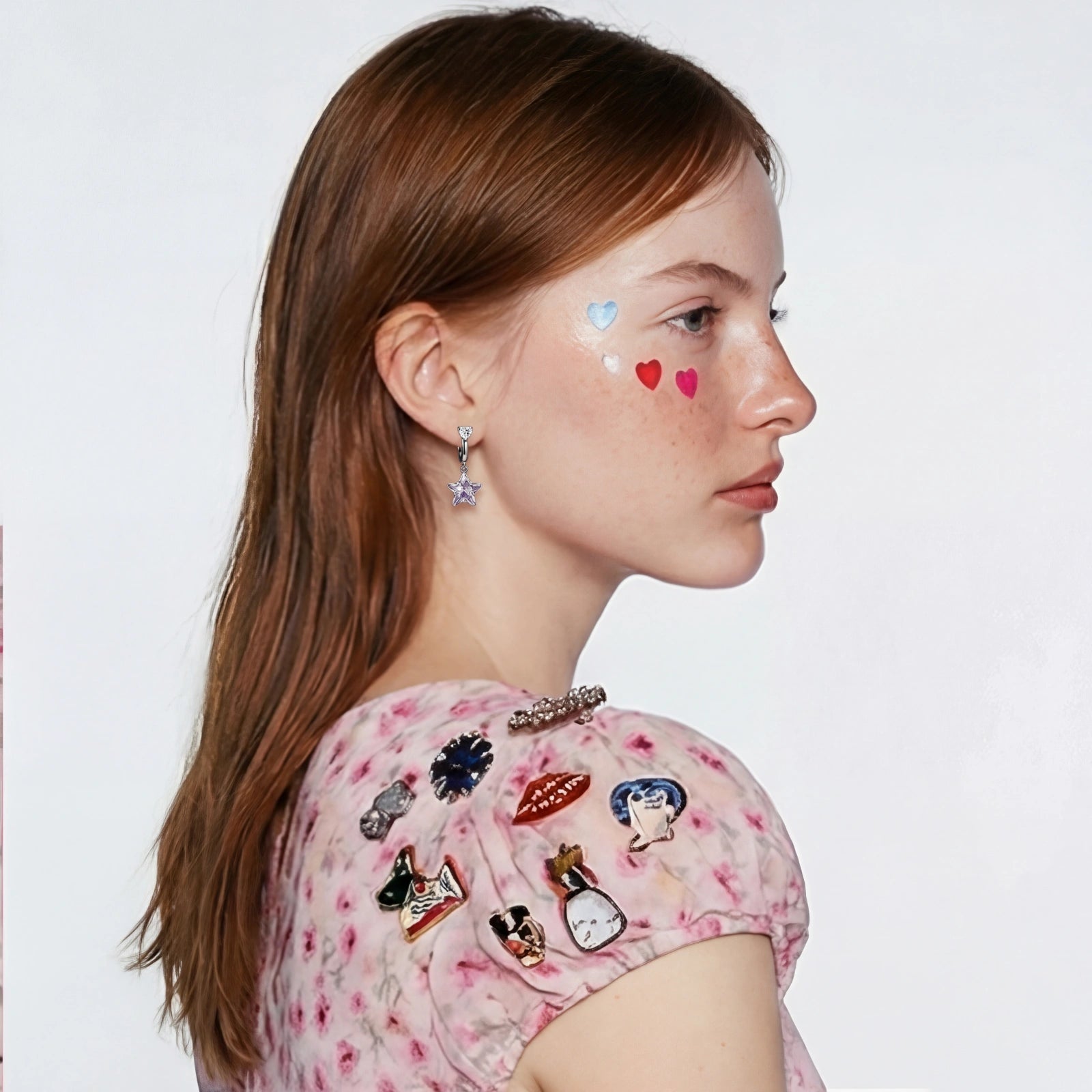 Huggie earrings featuring lilac star motifs and heart accents, elegantly styled with a light pink outfit and decorative elements.