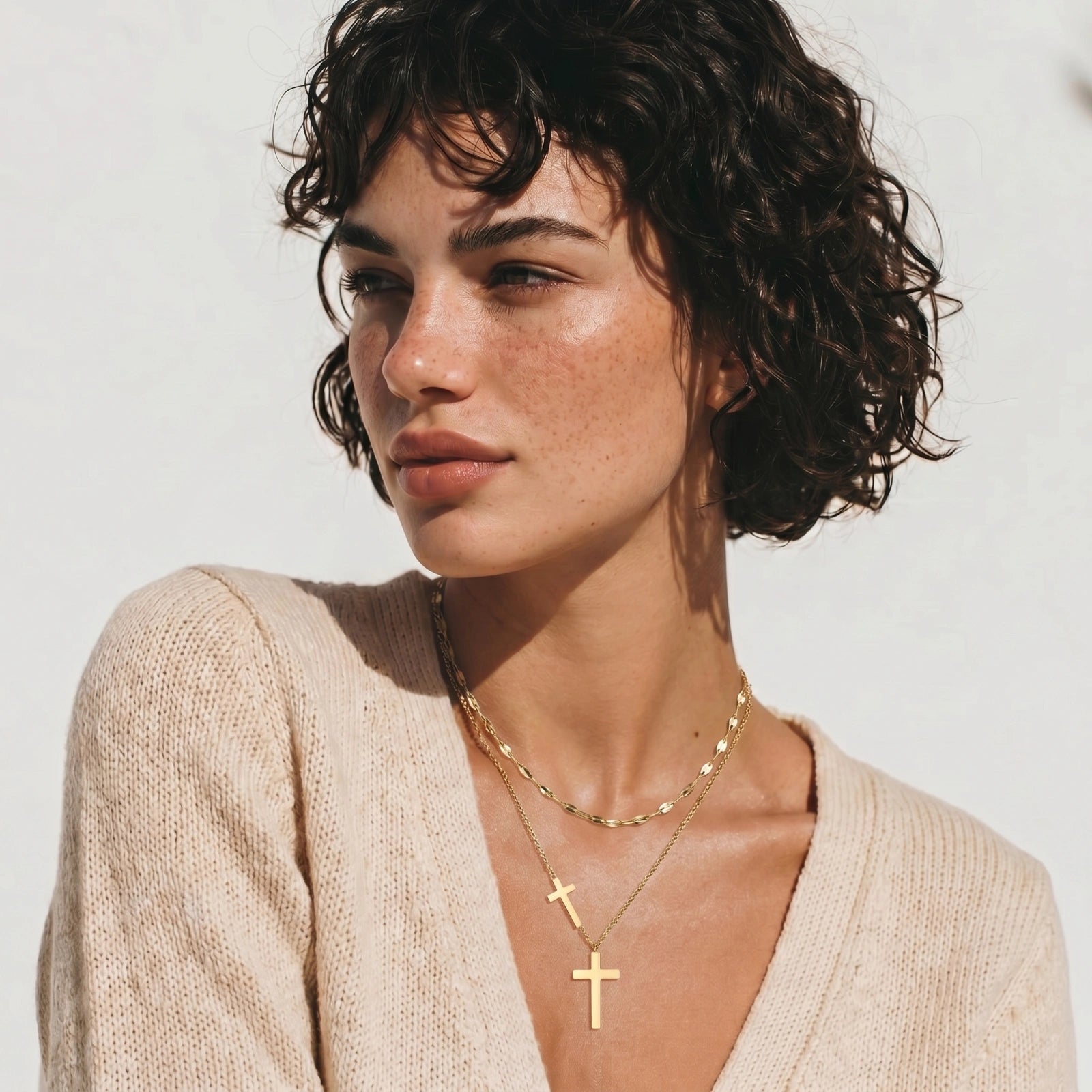 Layered gold necklace set featuring a shorter mirror-link chain and a longer chain with three polished cross pendants.
