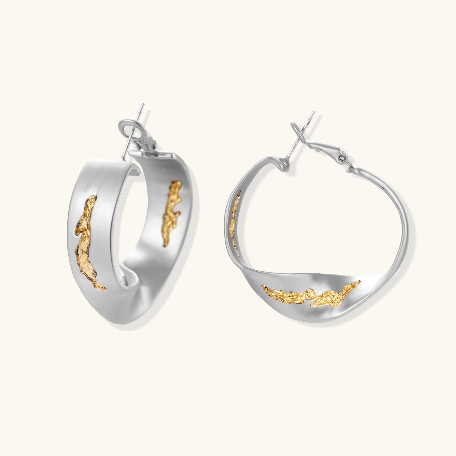 Twisted silver hoop earrings with textured gold accents, embodying elegance and sophistication.