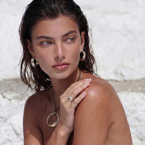 Model showcasing twisted hoop earrings with a textured surface, exuding elegance alongside a simple necklace.