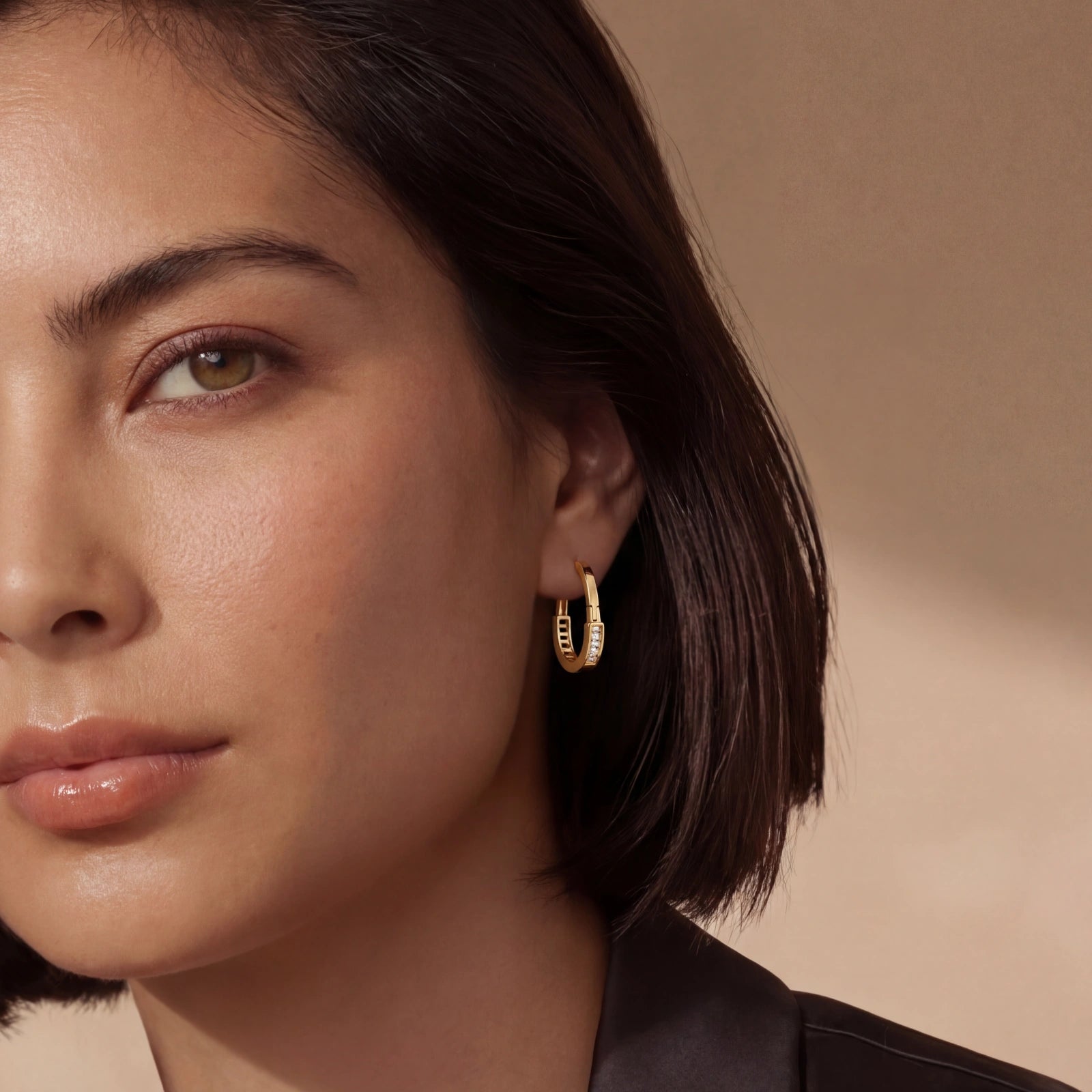 Huggie hoop earrings in gold, elegantly worn close to the earlobe, showcasing their refined design.